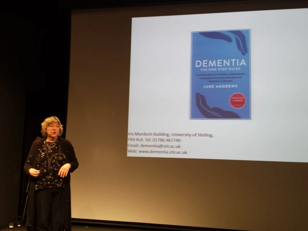 A speaker presenting a dementia book cover on a projection screen